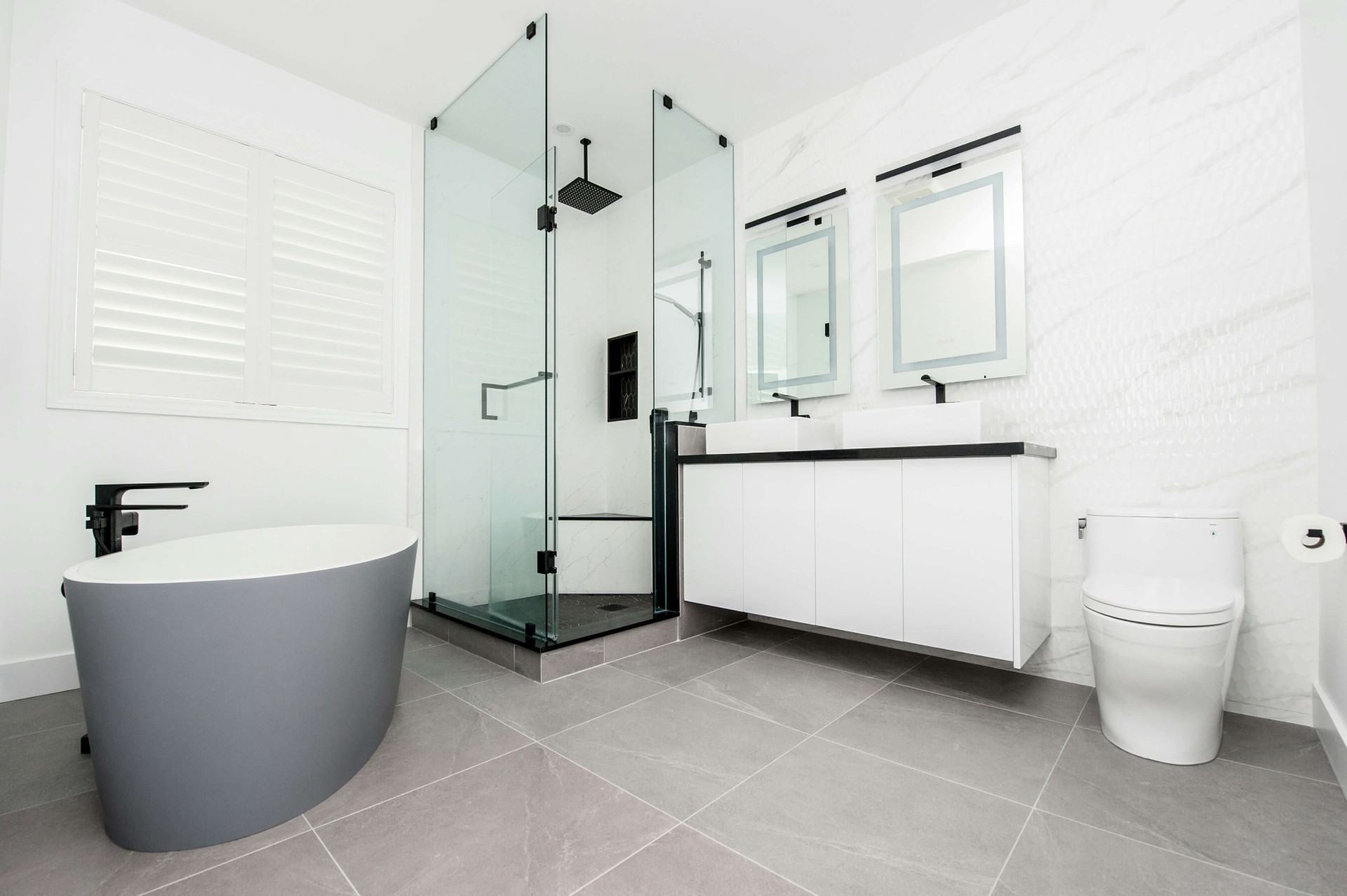 Vaalea moderni kylpyhuone lasisuihkulla ja vaaleanharmailla lattialaatoilla